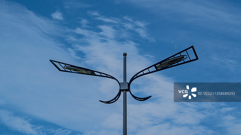 擎起蓝天白云的蝴蝶式路灯。白云从路灯上空飘走。图片素材