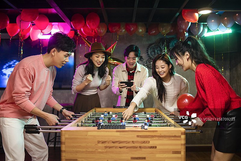 快乐的年轻人玩桌上足球图片素材