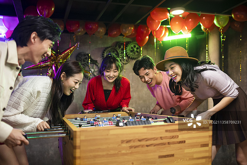 快乐的年轻人玩桌上足球图片素材