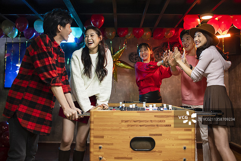 快乐的年轻人玩桌上足球图片素材