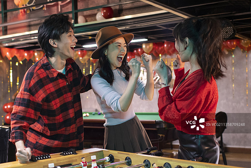 快乐的年轻人玩桌上足球图片素材