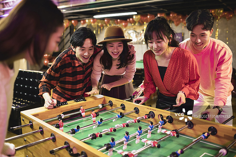 快乐的年轻人玩桌上足球图片素材