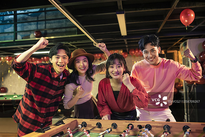 快乐的年轻人玩桌上足球图片素材