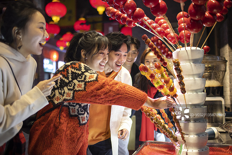 年轻朋友们逛街吃冰糖葫芦图片素材