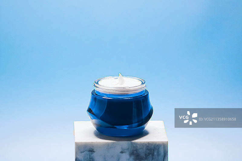 抗衰老护肤和化妆品：蓝色背景上的美容面霜图片素材