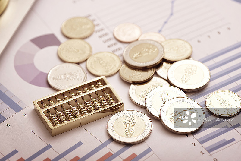 金融概念——放在财务数据报表上的算盘和硬币图片素材