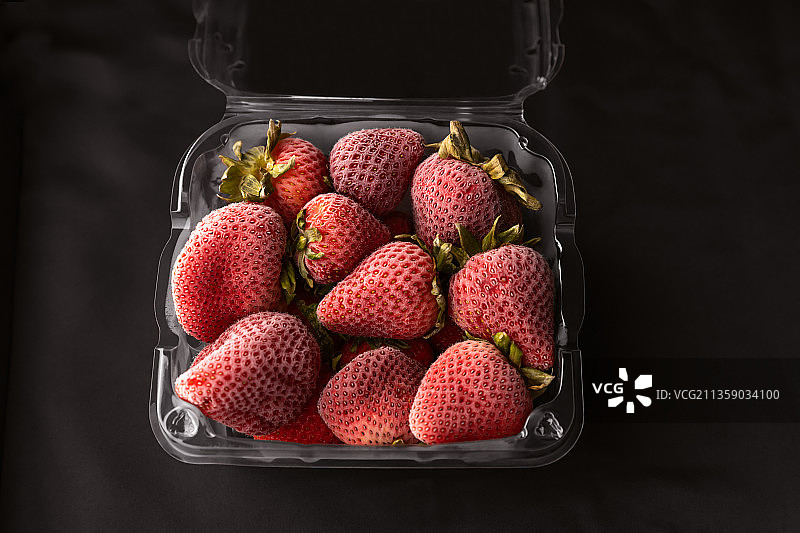 黑色背景下，容器中的草莓特写图片素材