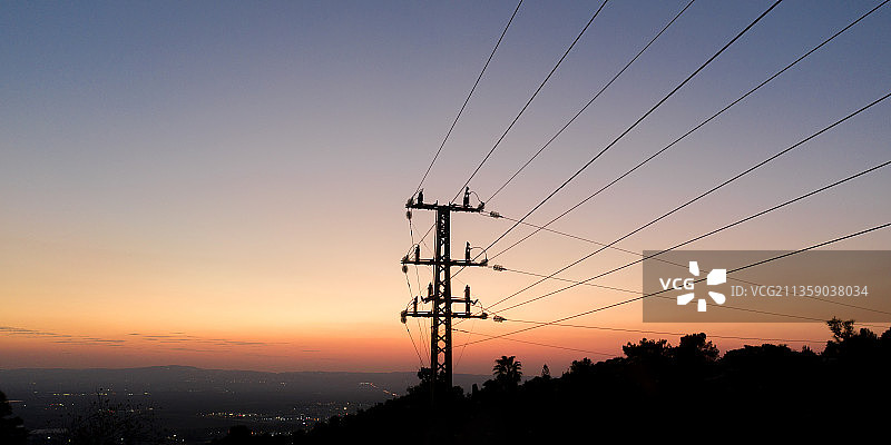 低角度拍摄日落时天空下的电塔轮廓图片素材