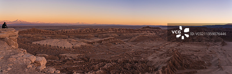 日落时分，男人坐在岩石上，以天空为背景图片素材