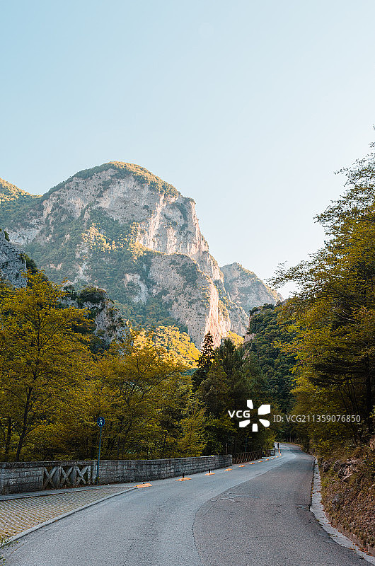 在晴朗的天空下，通往群山的空旷道路图片素材