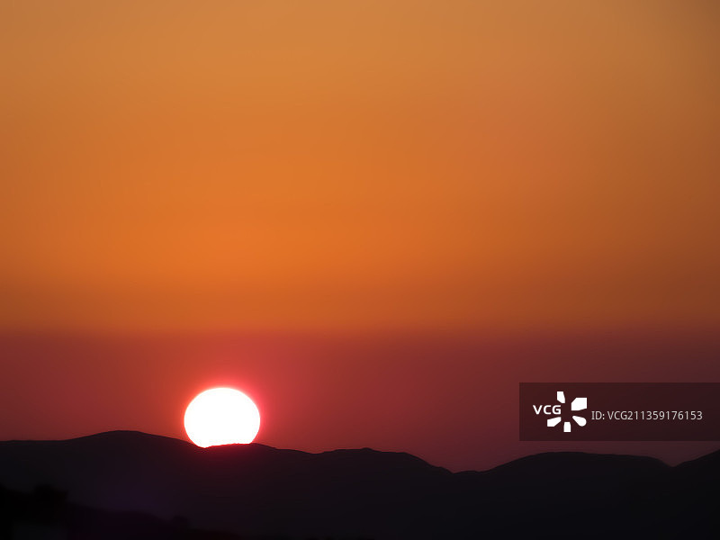 橘黄色天空映衬下群山剪影的风景图片素材