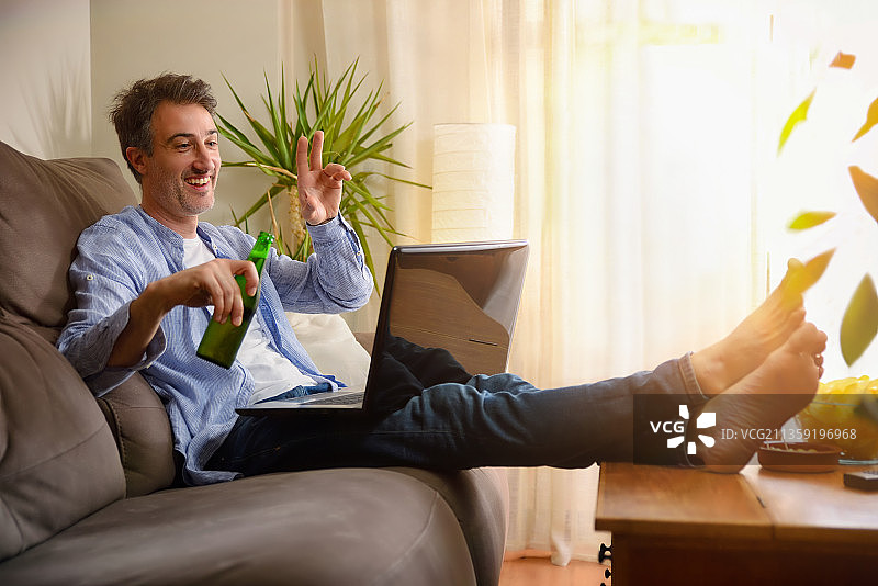 男人坐在沙发上吃零食开视频会议图片素材