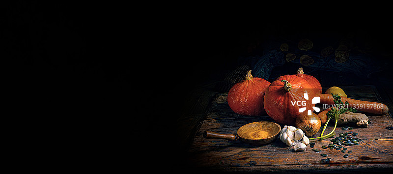 黑色背景下的南瓜与干树叶特写图片素材