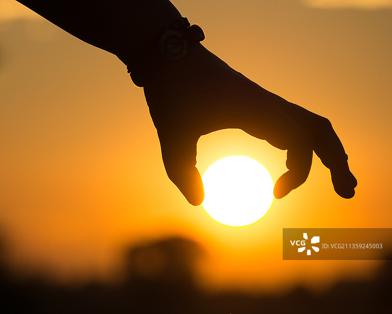 日落时手持太阳的轮廓局部特写图片素材