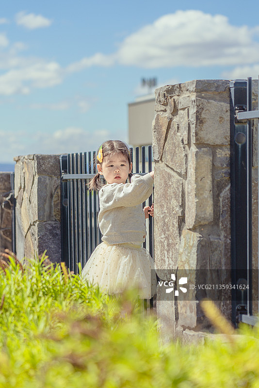 别墅庭院围栏处可爱的小女孩图片素材