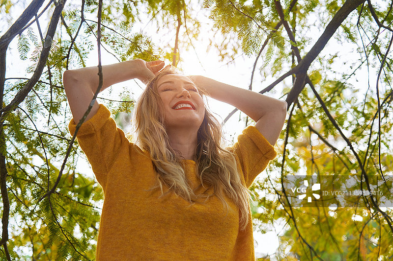 微笑的金发女人在度假时进行森林浴图片素材