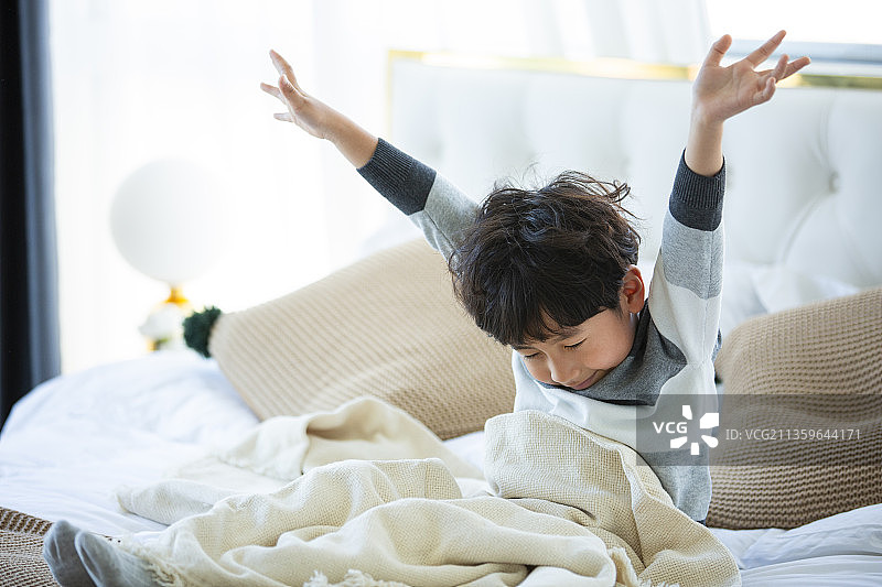 小男孩在卧室床上伸懒腰图片素材