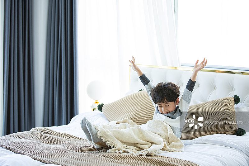 小男孩在卧室床上伸懒腰图片素材