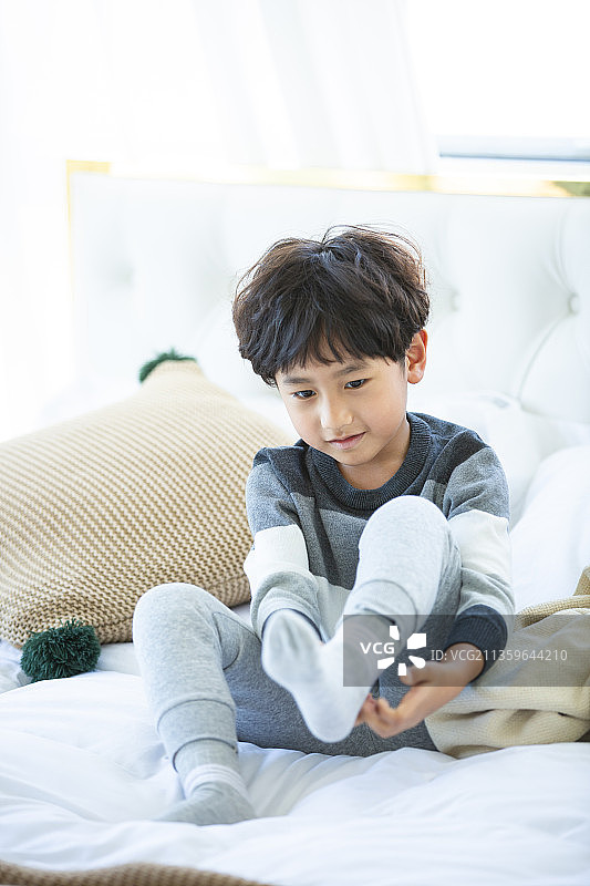 小男孩在卧室起床穿袜子图片素材