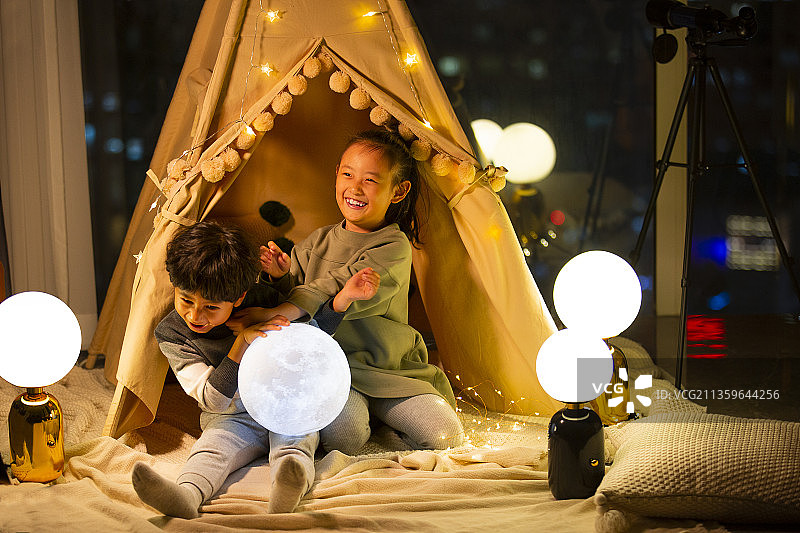 姐姐和弟弟在客厅露营拿着月球灯玩耍图片素材