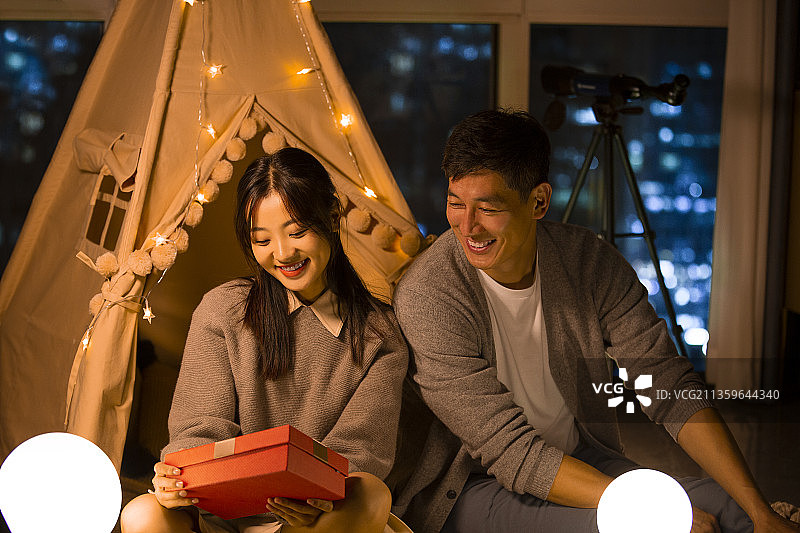 甜蜜情侣在客厅露营送礼物图片素材