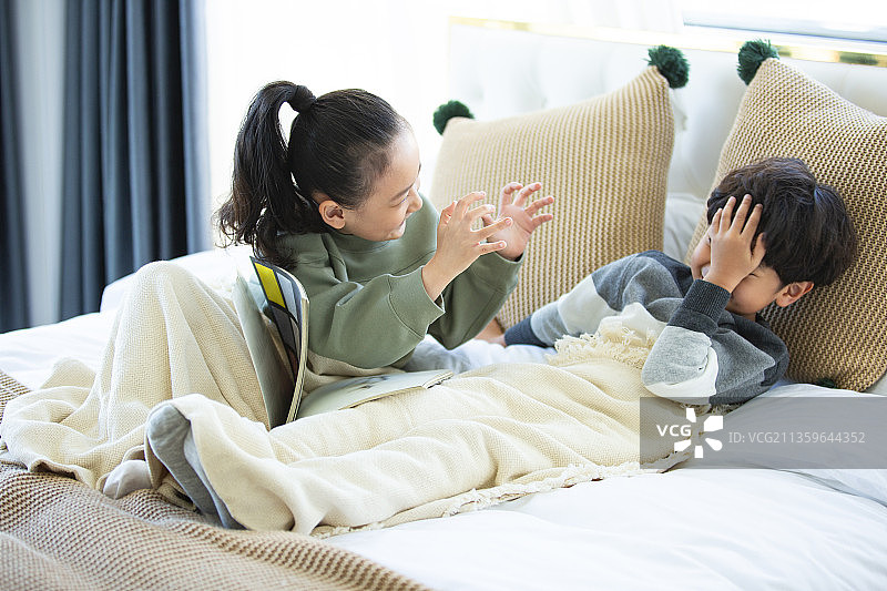 姐姐给弟弟讲故事在卧室床上图片素材
