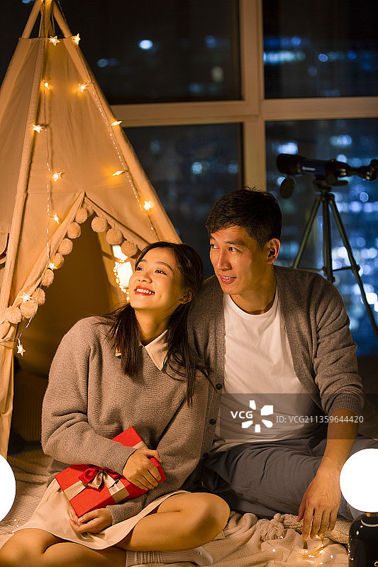 甜蜜情侣在客厅露营送礼物图片素材