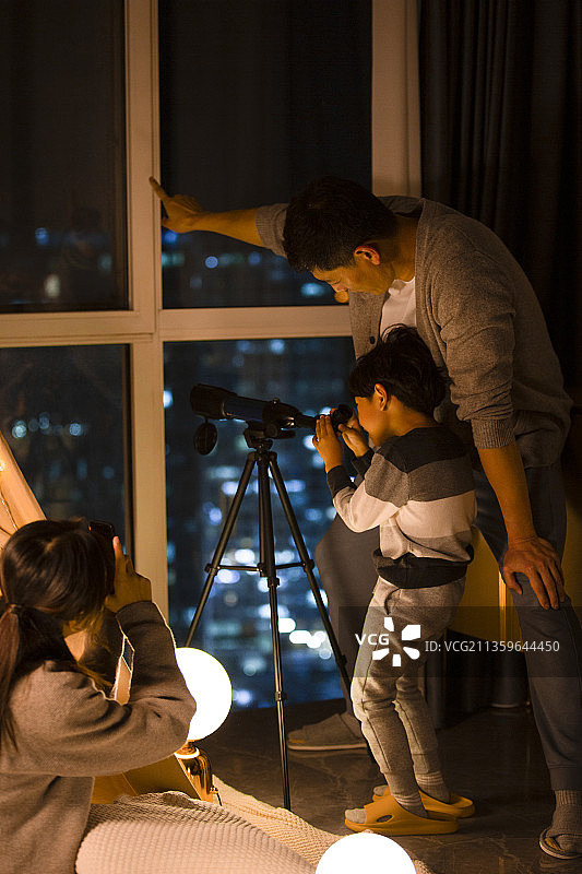 爸爸教儿子看天文望远镜，妈妈使用手机给父子俩拍照录像图片素材