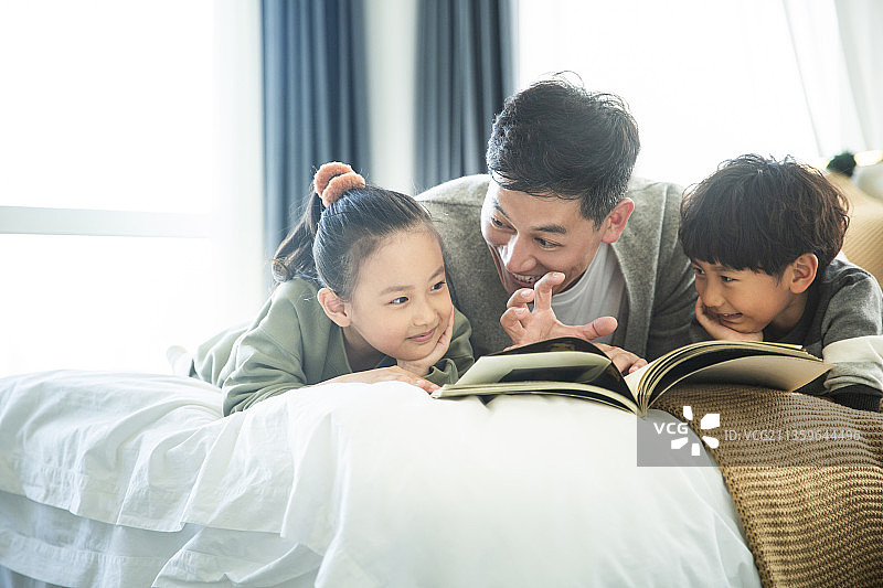 爸爸给儿子和女儿读书讲故事在卧室图片素材