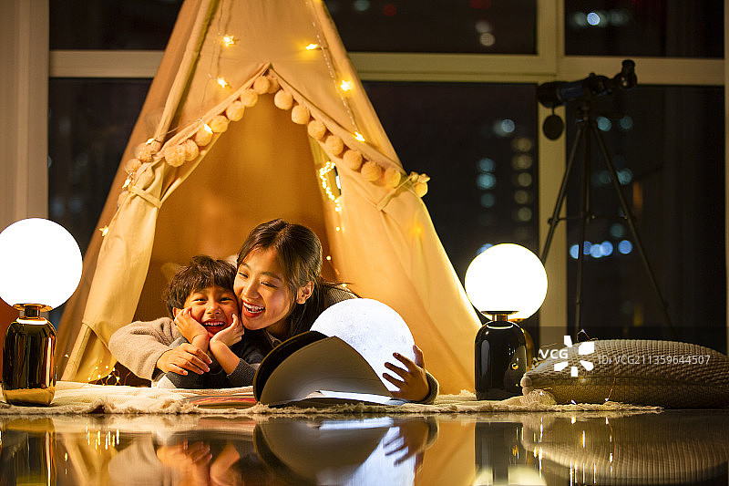 快乐母子在客厅露营拿着月球灯讲故事图片素材