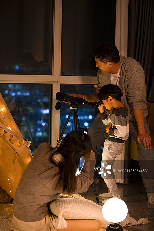 一家三口在客厅使用天文望远镜和手机拍照录像图片素材