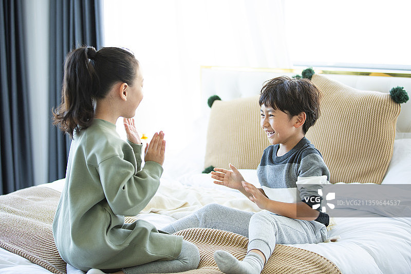 姐姐和弟弟在卧室床上玩拍手游戏图片素材