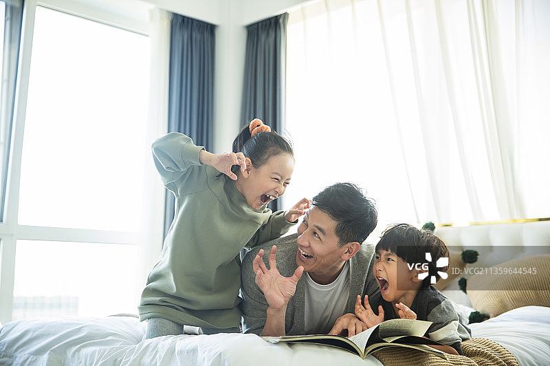 爸爸给儿子和女儿读书讲故事玩耍在卧室图片素材