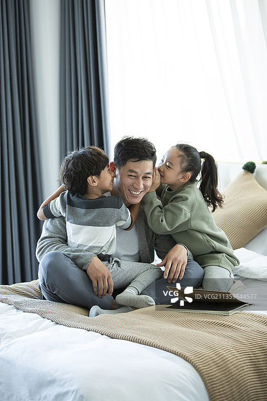 两个孩子在爸爸耳边悄悄说话在卧室图片素材