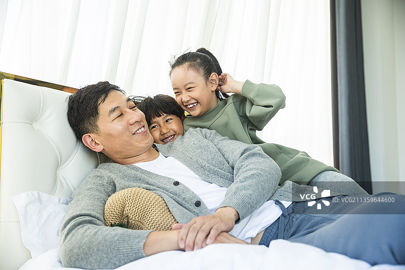 两个孩子恶作剧打扰爸爸睡觉在卧室图片素材