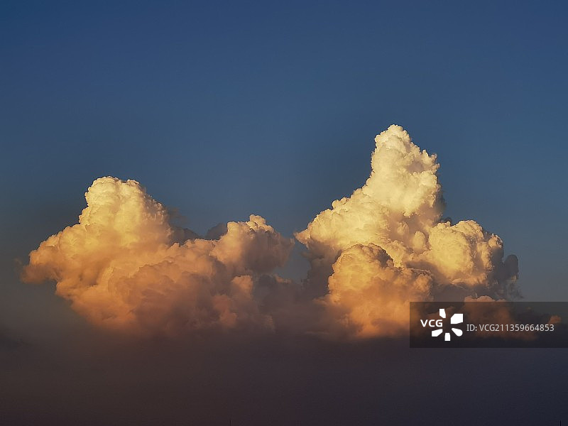 日落时分，蓬松的云朵在夕阳的晕染下染上渐变的橘色柔光图片素材