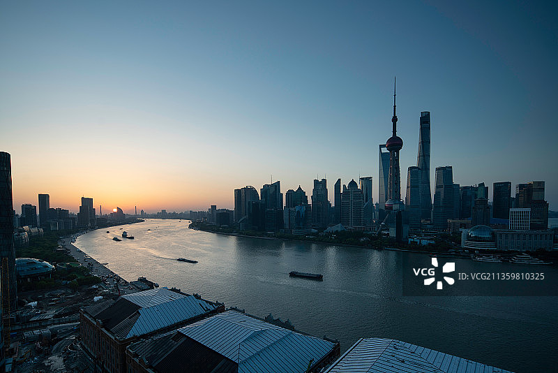 中国上海，国际著名都市，繁华的陆家嘴金融区傍晚。落日的余晖照亮黄浦江面。美丽的城市天际线。图片素材