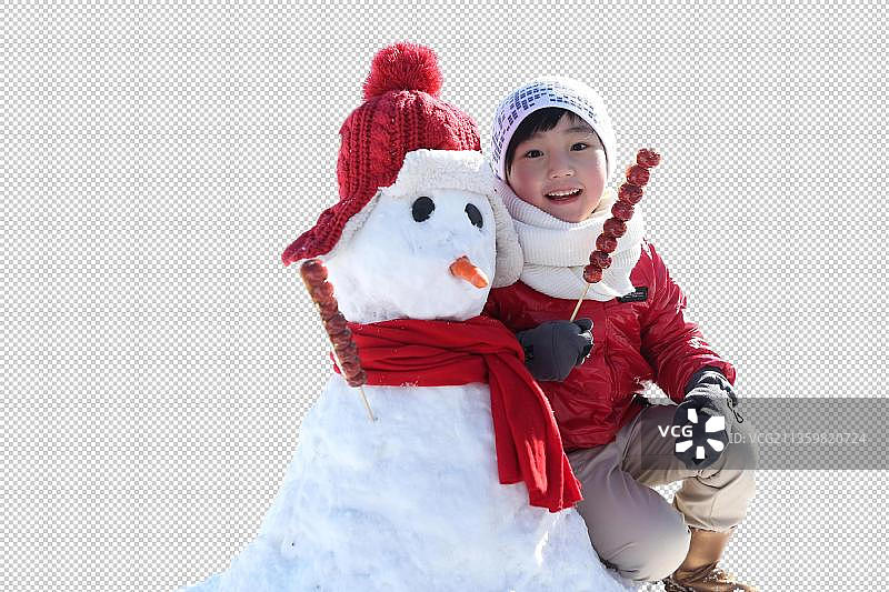 男孩拿着糖葫芦和雪人在雪地上图片素材
