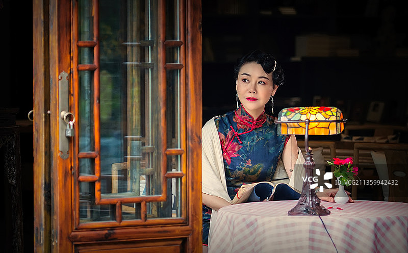 穿着旗袍的女人坐在一座古宅的窗前图片素材