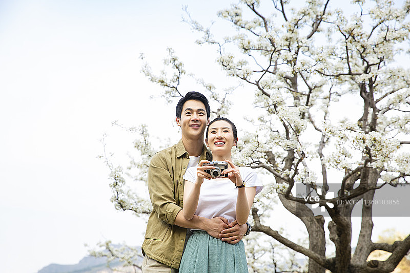 甜蜜情侣在户外旅行拿着相机看照片图片素材