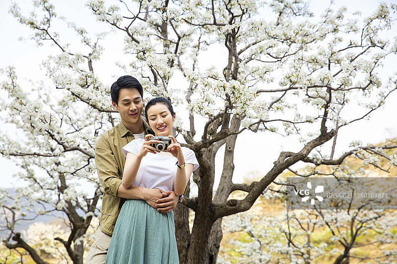 甜蜜情侣在户外旅行拿着相机看照片图片素材