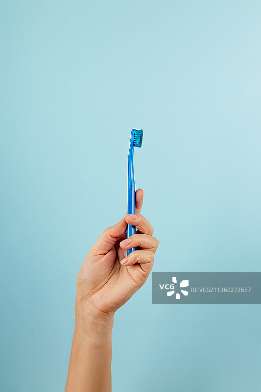 裁剪的手拿着牙科设备，蓝色背景图片素材