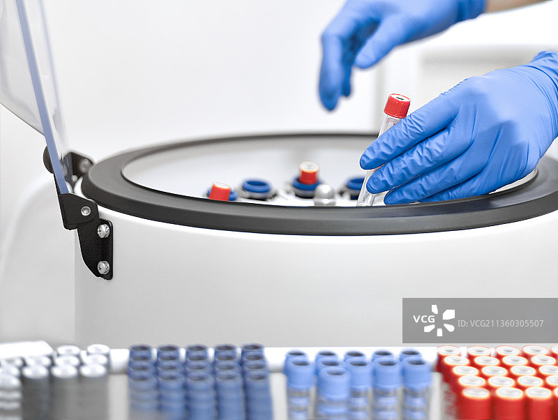 戴手套的手将试管放入实验室离心机图片素材
