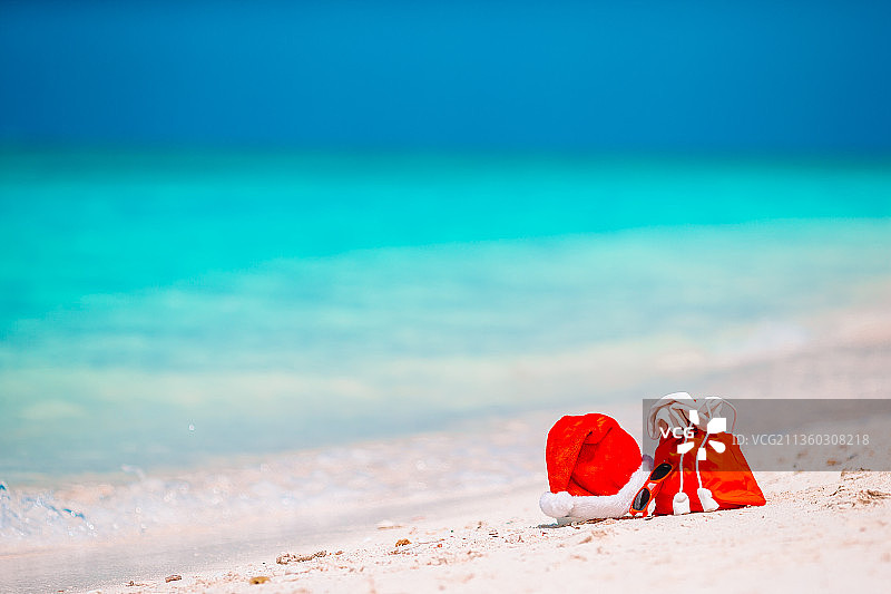 戴着圣诞帽的配饰在白色热带海滩上图片素材