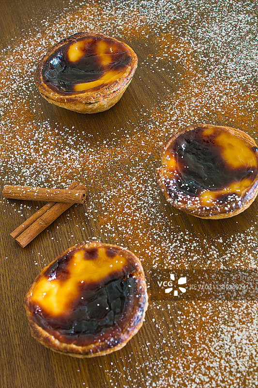 肉桂粉和糖粉点缀的三个传统葡萄牙蛋挞图片素材