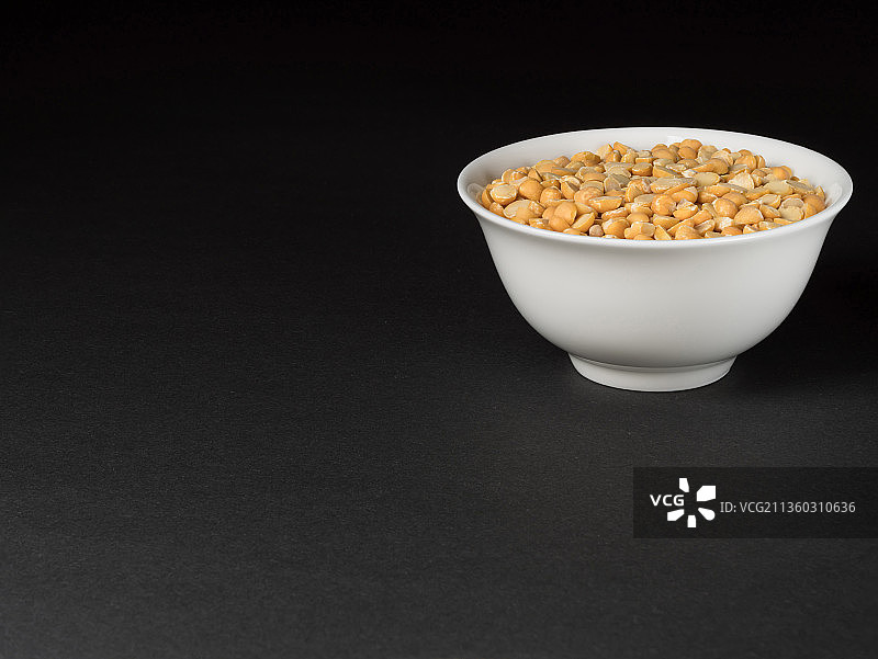 黑色背景上的干燥黄色去皮豌豆图片素材