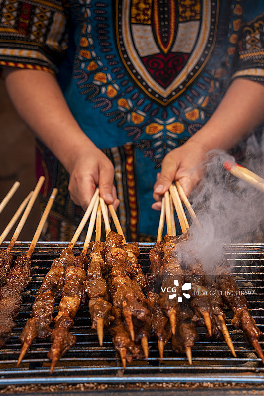 身穿民族服饰制作特色美食羊肉串图片素材