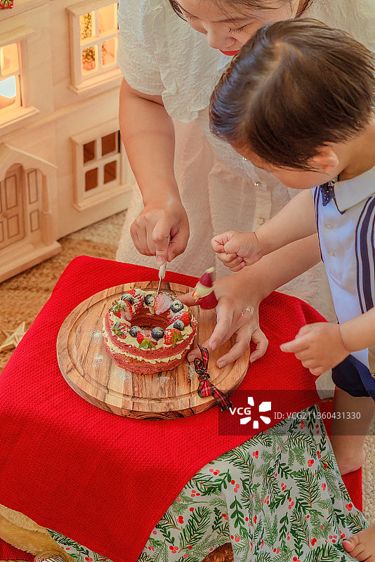 快乐男孩与妈妈一起切圣诞蛋糕图片素材