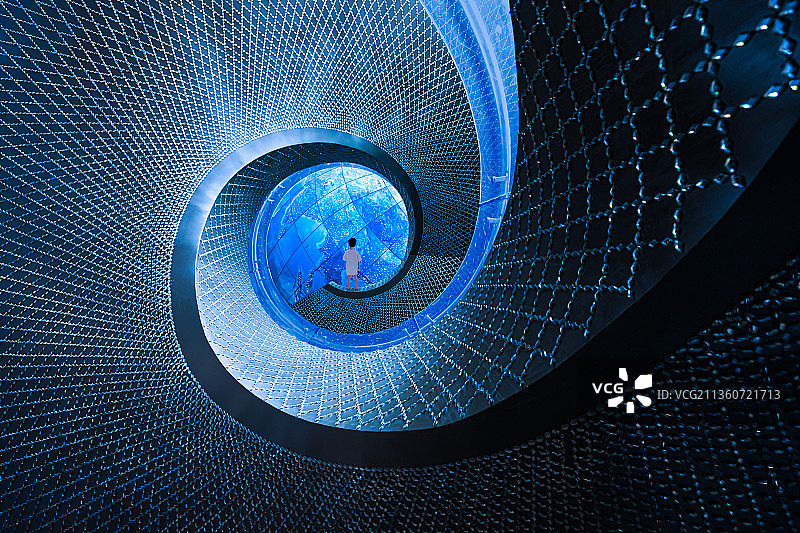 一个站在蓝色螺旋楼梯顶端看地球星空的小男孩背影图片素材