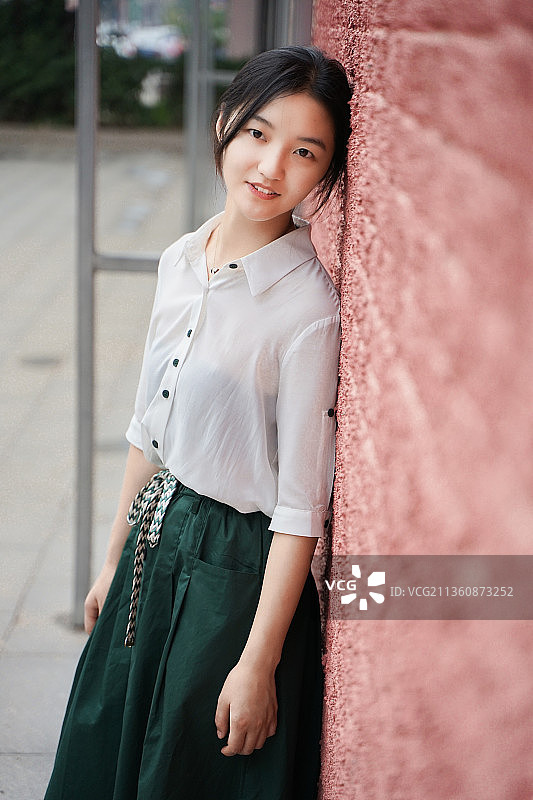 少女靠在墙上注视镜头侧脸图片素材
